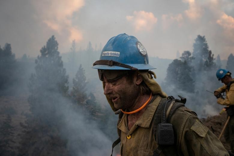 Kirk McDusky, a member of the Prineville Hotshot Crew, walks past smoke rising from the Brattain Fire in the Fremont National Forest in Paisley, Oregon. REUTERS/Adrees Latif  